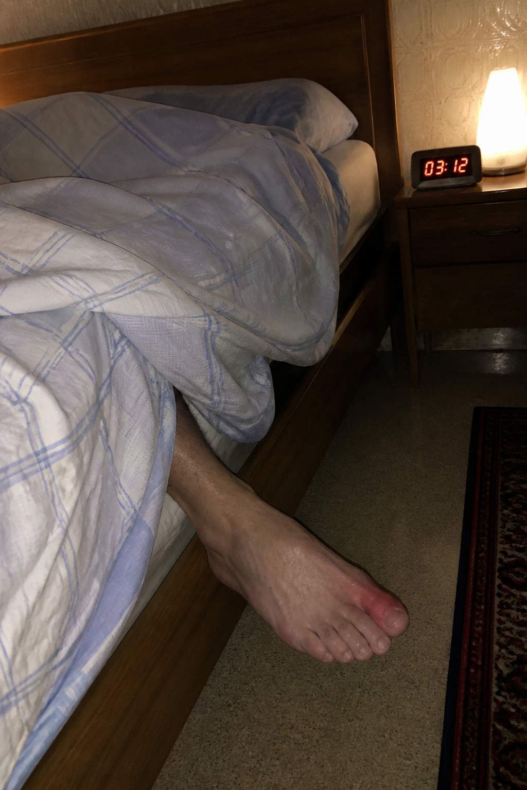 Il piede fuori dal lenzuolo, lampada sul comodino.